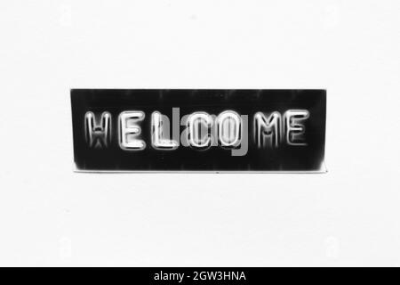 Black color banner that have embossed letter with word welcome on white paper background Stock Photo