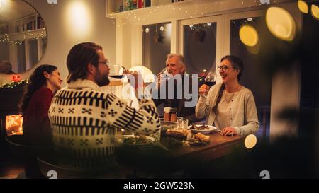 European family sitting at dinner table having wine. Family having thanksgiving dinner at home. Stock Photo