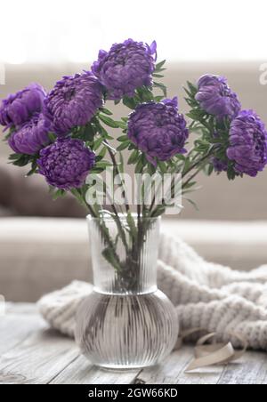 A bouquet of blue chrysanthemums in a glass vase on the table in the interior of the room. Stock Photo