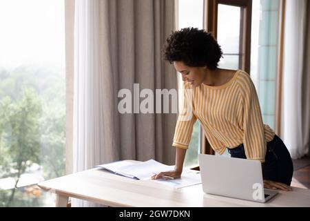 Happy young african ethnicity business lady working standing at table. Stock Photo