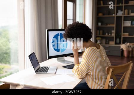 Concentrated young african ethnicity employee multitasking in office. Stock Photo
