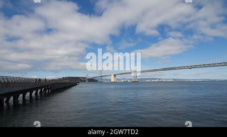 Bridge Over Calm Sea Against Cloudy Sky