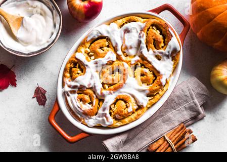 Pumpkin apples cinnamon rolls and organic pumpkins and apples  close up. Seasonal autumn homemade pastry - cinnabons for breakfast. Stock Photo