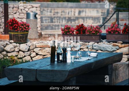 Rustic wooden table in Mediterranean garden prepared for dinner Stock Photo