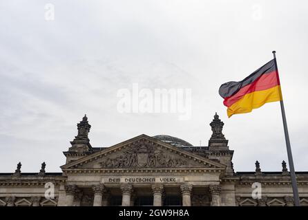 Berlin, Germany. 03rd Oct, 2021. A Germany flag flies in front of the Reichstag on German Unity Day. The German Unity Day Act came into force on 4 August 1953. In future, 17 June was to serve as a statutory national memorial day to commemorate the 1953 uprising in the GDR. Since German reunification in 1990, the 'Day of German Unity' has been celebrated on 3 October. Credit: Paul Zinken/dpa/Alamy Live News Stock Photo