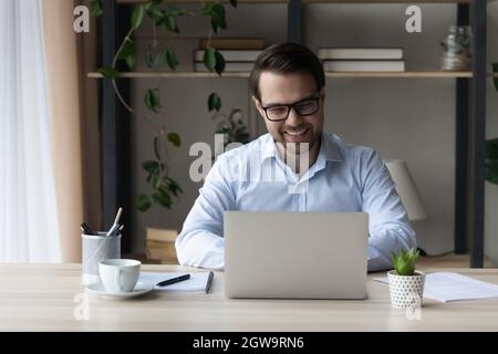 Smiling confident businessman in glasses working on laptop online Stock Photo