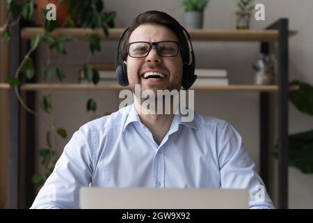 Close up overjoyed man in headphones and glasses laughing Stock Photo