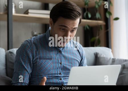 Close up overjoyed surprised man looking at laptop screen Stock Photo
