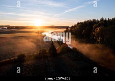 Golden sunrise over foggy river and agricultural fields in autumn. Stock Photo