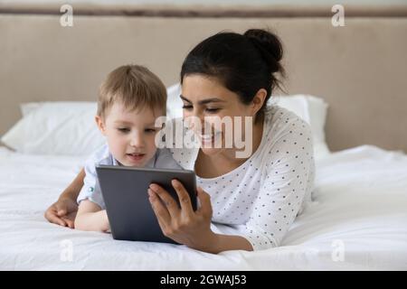 Affectionate young indian mother using tablet with little son. Stock Photo