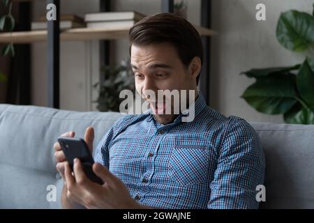Head shot overjoyed surprised man looking at smartphone screen Stock Photo