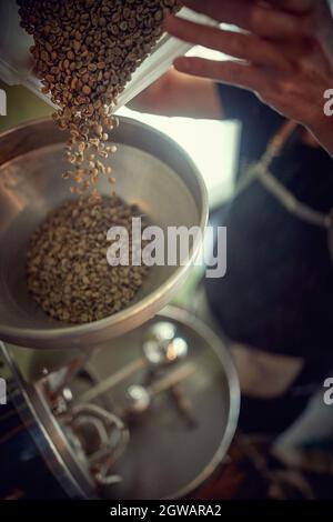 drip raw coffee over a coffee roasting machine. Stock Photo