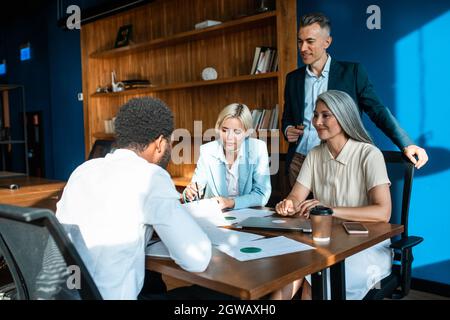 cinematic image of a multiethnic business team. Group of employees working together on a project in the office Stock Photo