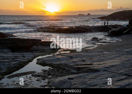 Sunset over the Atlantic Ocean near Padstow, Cornwall, England, UK. A yellow sunset as the sun drops below the horizon with warm reflections in the wa Stock Photo
