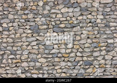 seamless texture of ugly sharp stone wall with concrete between rocks Stock Photo