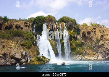 Duden Waterfall In Antalya Turkey. Mediterranean Sea. Small Boat With People On The Waves