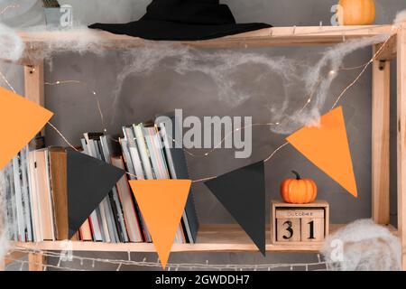 Happy Halloween date October 31 on wooden calendar. bookshelf decoration with orange black flags. Autumn holiday concept. Stock Photo