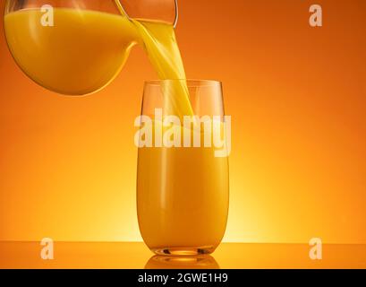 Orange juice pouring into glass with splash Stock Photo