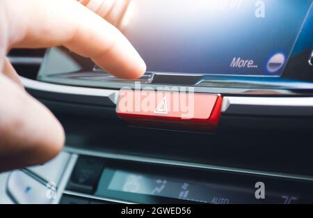 Driver hand pressing hazard light button switch on dashboard in the car, Automotive parts concept. Stock Photo