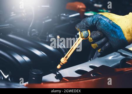 Mechanic hand pulling up oil dipstick of the car engine for checking oil level, Car maintenance service concept. Stock Photo