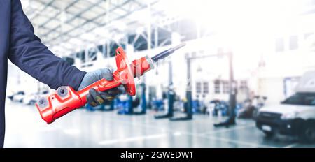 Mechanic hand holding a front shock absorber of the car in the repair garage Stock Photo