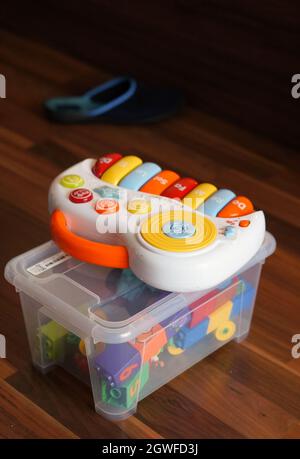 POZNAN, POLAND - Nov 13, 2015: A plastic toy keyboard on a plastic box filled with lego blocks on a wooden floor Stock Photo