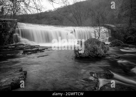 Long black and white exposure of the Monsal Dale Weir waterfall and River Wye on the Monsal Trail in the Peak District Stock Photo