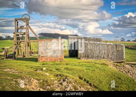 The grade II listed corrugated iron winding house and pit-head wheel headgear at Magpie Mine, Sheldon, a preserved lead mine in the Peak District Stock Photo