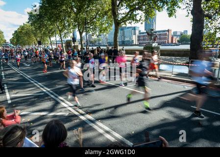 London, UK.  3 October 2021. Runners pass mile 25 on the Embankment in the London Marathon, the first time it has been held since April 2019 due to the Covid-19 pandemic.  Over 36,000 elite athletes, club runners and fun runners are taking part in the mass event, with another 40,000 people taking part virtually. Credit: Stephen Chung / Alamy Live News Stock Photo