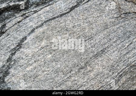 Untreated natural texture of gray granite close-up. Abstract background, texture, pattern, wallpaper. Stock Photo