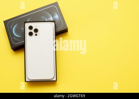 STARIY OSKOL, RUSSIA - JULY 5, 2021: Unboxing new iPhone 12 pro max on a yellow background with copy space Stock Photo