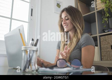 Happy businesswoman working on laptop at home. Young woman working with a smile. Beautiful female freelancer working using laptop at home office Stock Photo