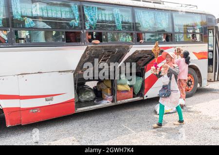 Woman selling chicken on a stick to bus passengers at bus station, Seno, Laos Stock Photo