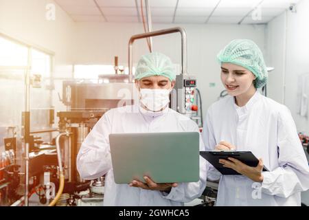 Factory staff worker check quality control in factory or industry research team collect data in beverage factory with laptop. Stock Photo