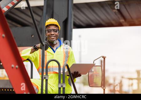 Portrait Black African staff worker happy smile working in cargo crane shipping logistic port. Stock Photo