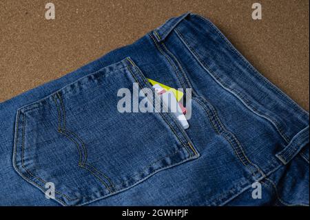 blue jeans with credit cards visible in the back pocket lie on a flat surface Stock Photo