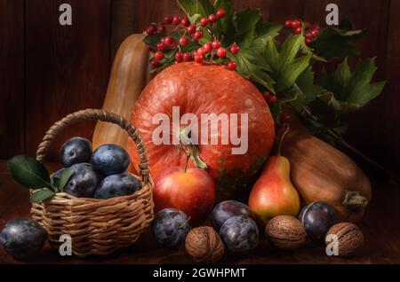 pumpkins, pears, plums and other berries and fruits in bulk on a dark wooden background in a rustic style Stock Photo