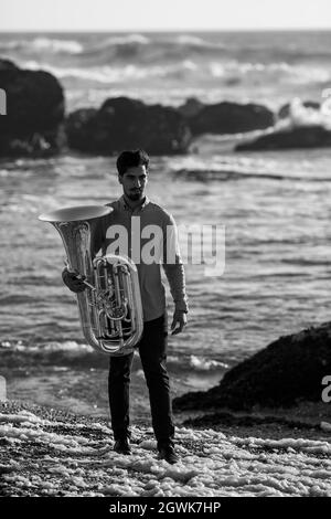 A man with a tuba on the seashore. Black and white photo. Stock Photo