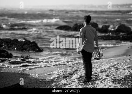 A musician man with a tuba on the seashore. Black and white photo. Stock Photo