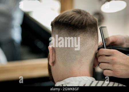 Confident man visiting hairstylist in barber shop. Back view Stock Photo