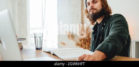 Bearded student study online at campus using laptop. Young man doing homework for university Stock Photo