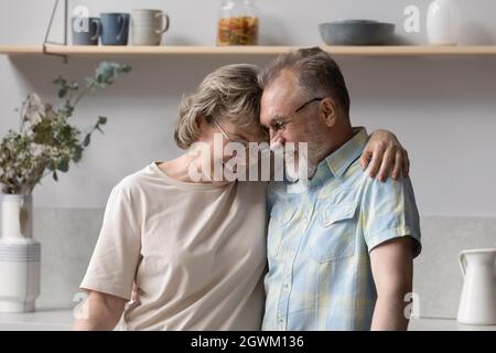Happy middle aged woman cuddling elderly senior husband. Stock Photo
