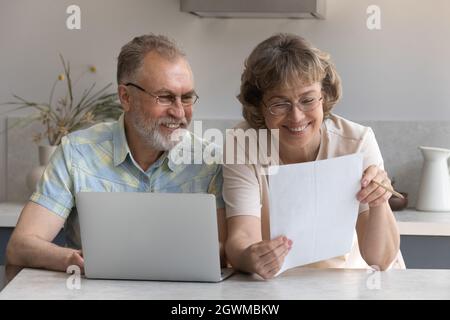 Happy middle aged old family couple reading paper document. Stock Photo