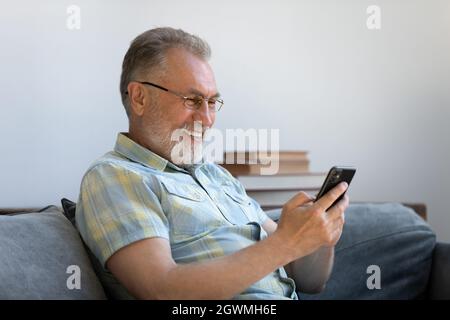 Joyful middle aged old man using cellphone. Stock Photo