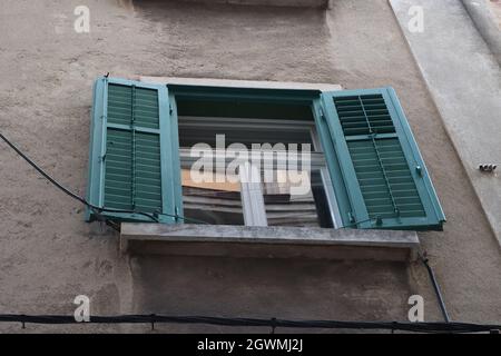 Window with green shutters in an old house Stock Photo