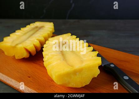 Cut in half of a peeled fresh ripe pineapple on cutting board Stock Photo