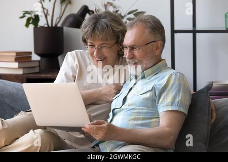 Happy bonding mature older family couple using computer. Stock Photo