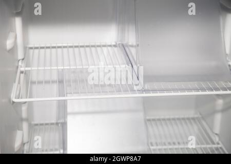 Empty shelves inside a clean, empty, white refrigerator Stock Photo