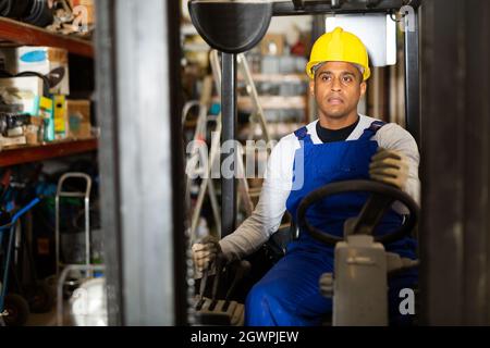 Latin American operator of forklift working in construction hypermarket Stock Photo