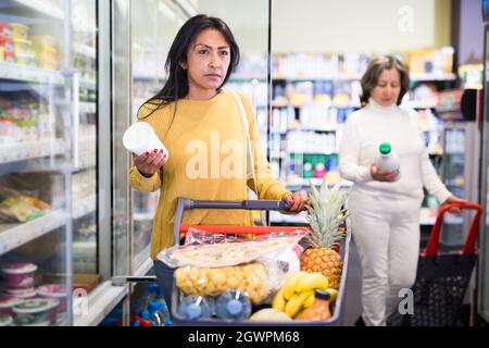 Latina choosing dairy products in fridge at grocery store Stock Photo